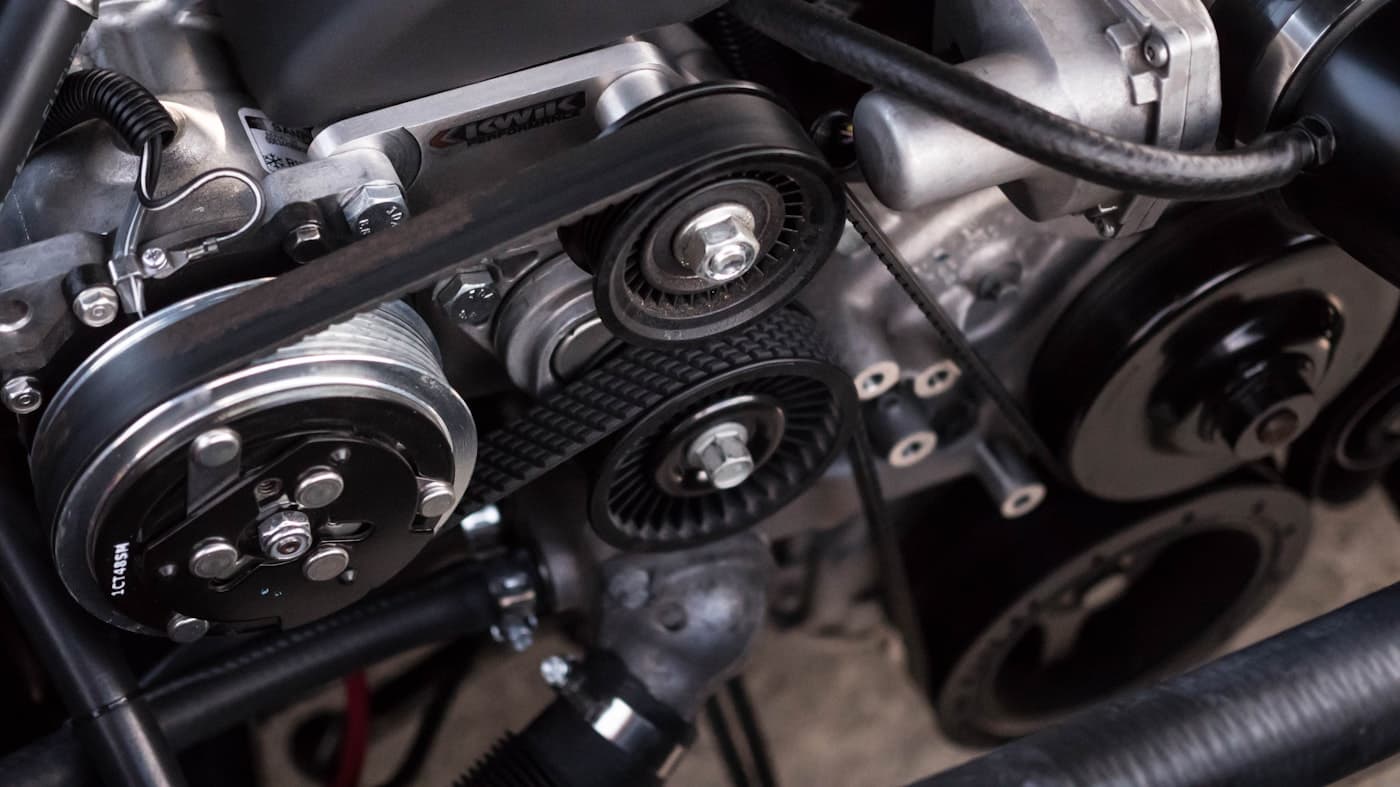 Close-up of a car engine bay showing belts and pulleys
