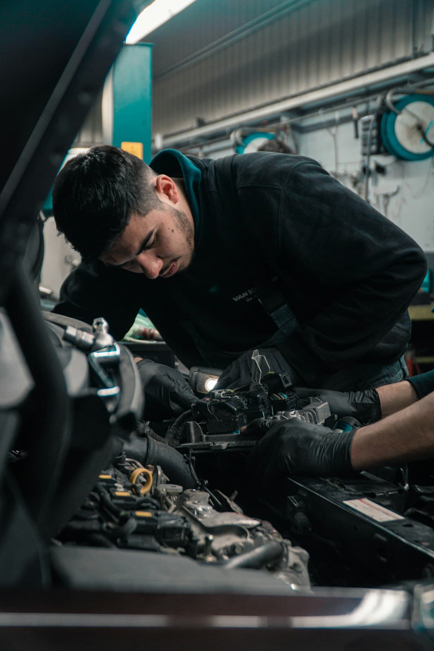 Mechanic leaning into an engine bay working under a workshop light